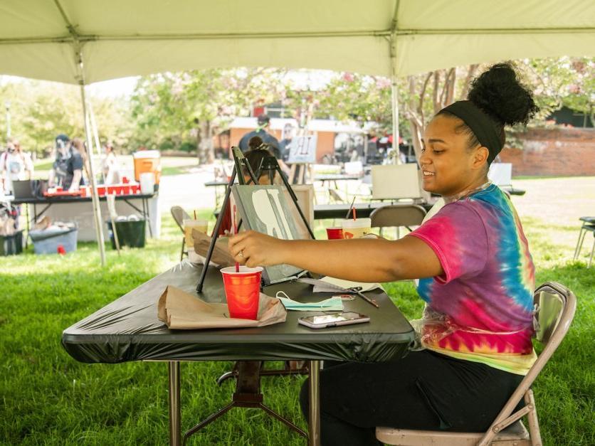 A student sits outside and paints